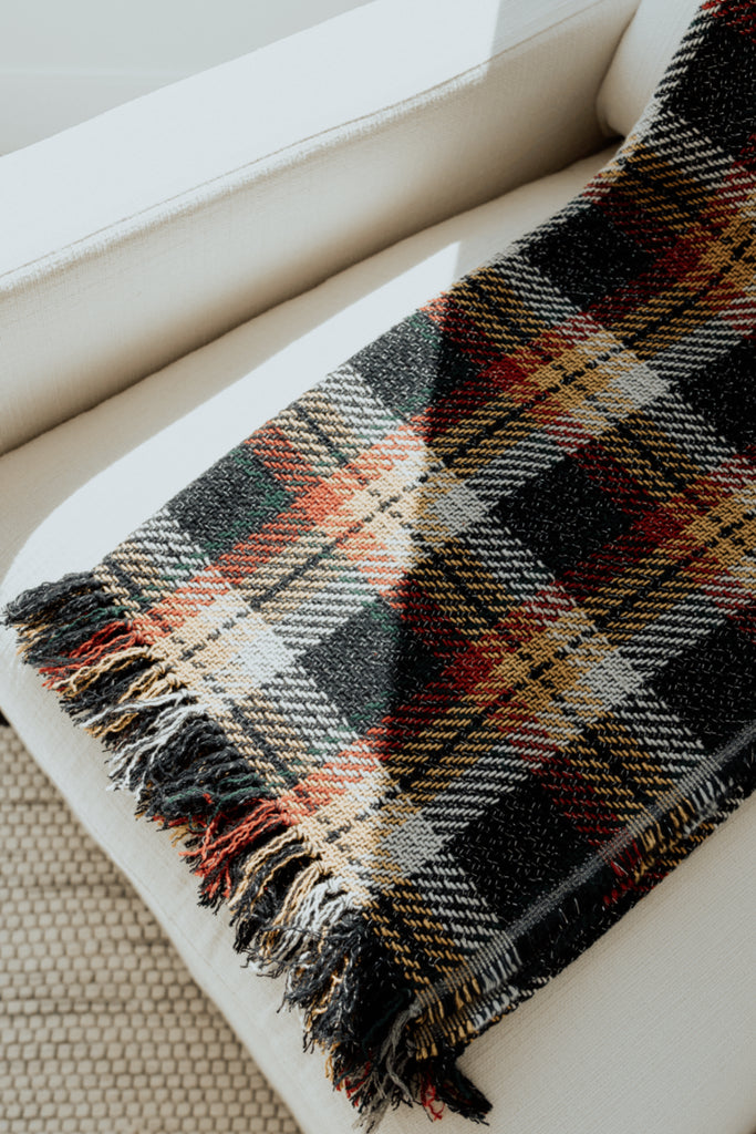 Common sizes of throw blankets this one is styled over a couch sofa with a plaid pattern