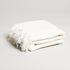 soft white throw blanket with tassels folded up and eyelash tassel